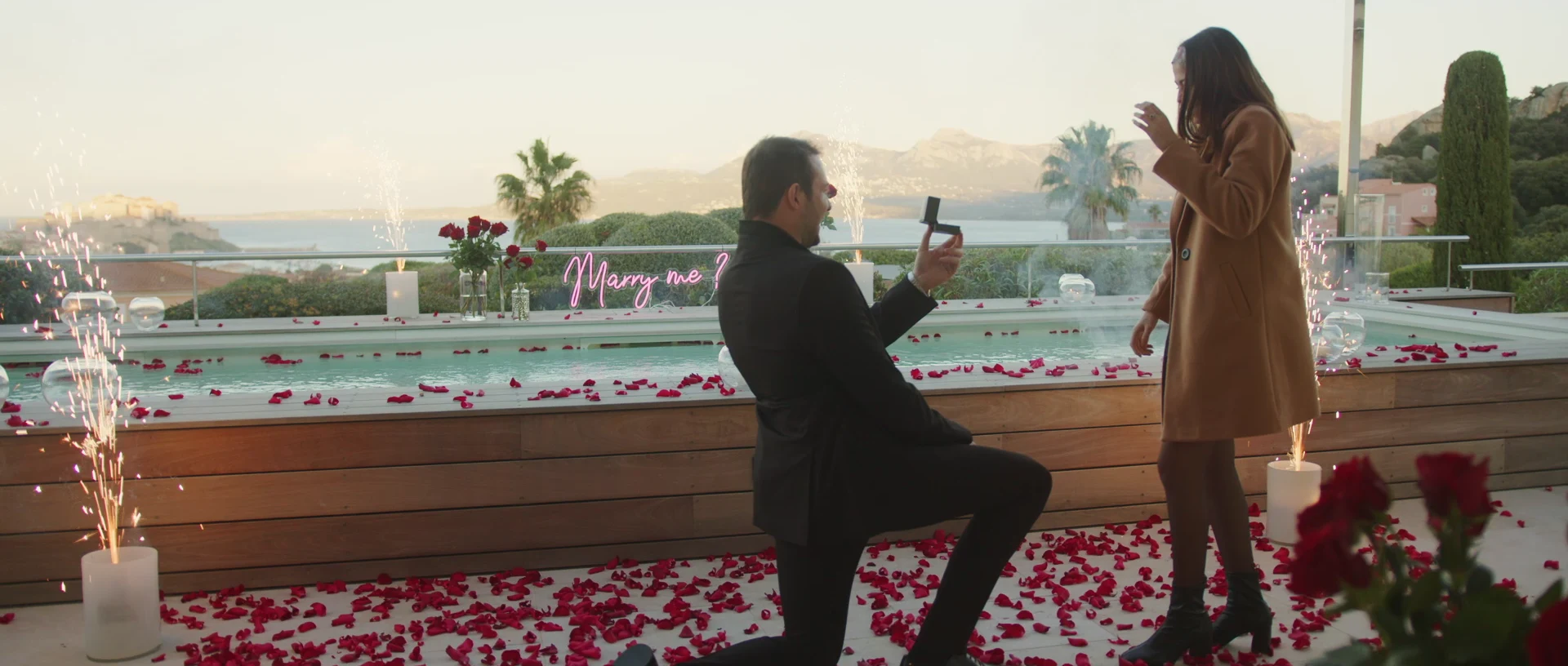 Surprise proposal on a terrace facing the sea, rose petals and sparklers