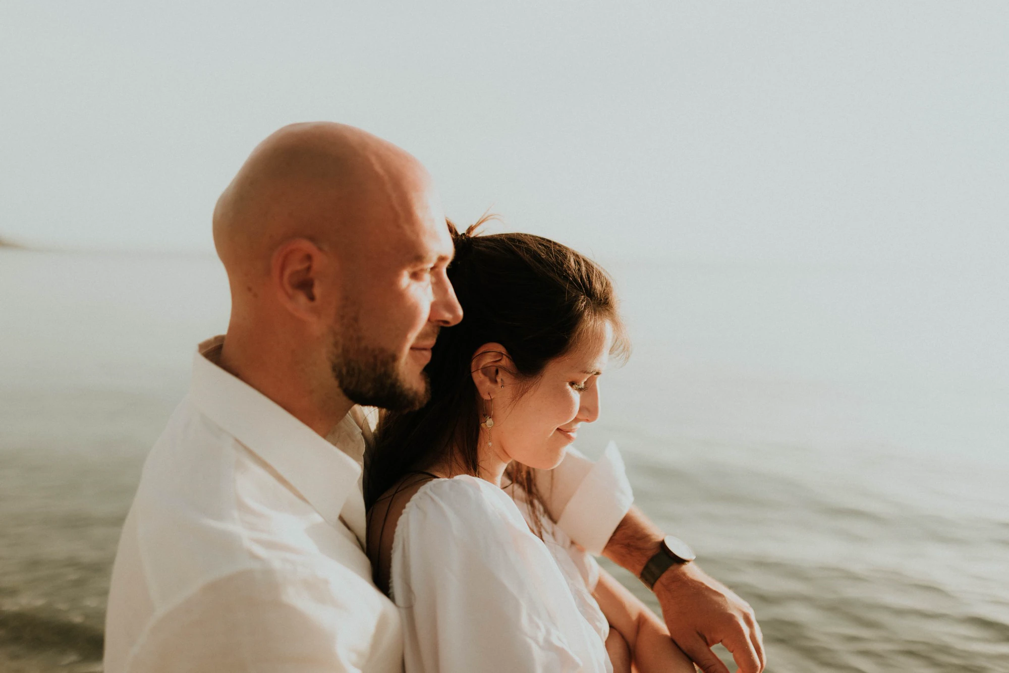 Couple embracing by the water in soft evening light