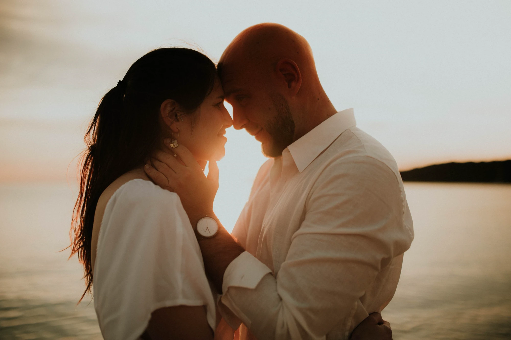 Couple forehead to forehead at sunset on Capo di Feno beach